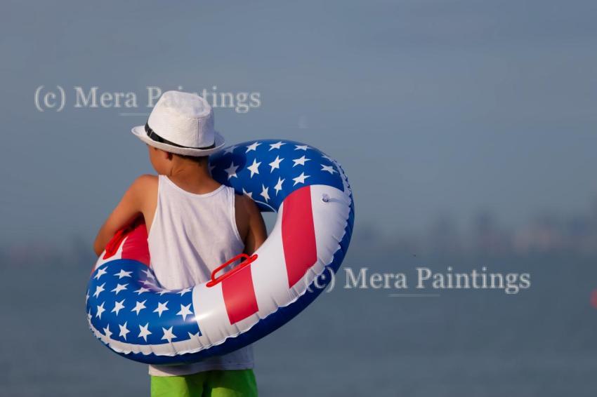 Child enjoying playing on beach with inflatable ring in american flag colors on sunny day