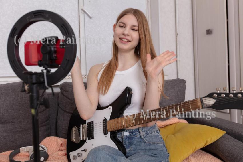 Young woman livestreams a music session while playing guitar in
