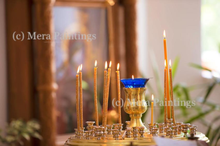 Beautifully arranged candles and decorative lamp illuminate a serene indoor space during a spiritual ceremony